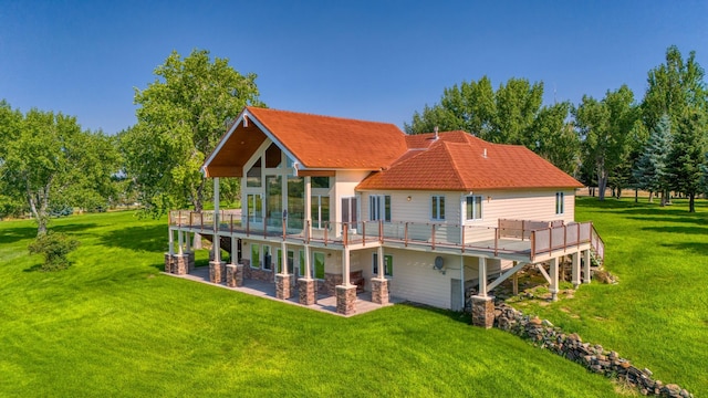 rear view of property with a deck, a patio, and a lawn