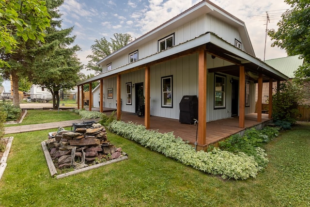 back of house featuring a fire pit, a deck, and a lawn