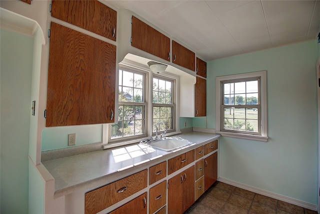 kitchen with dark tile patterned flooring, a wealth of natural light, and sink