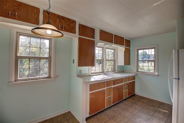 kitchen featuring decorative light fixtures, white refrigerator, dark tile patterned floors, and sink