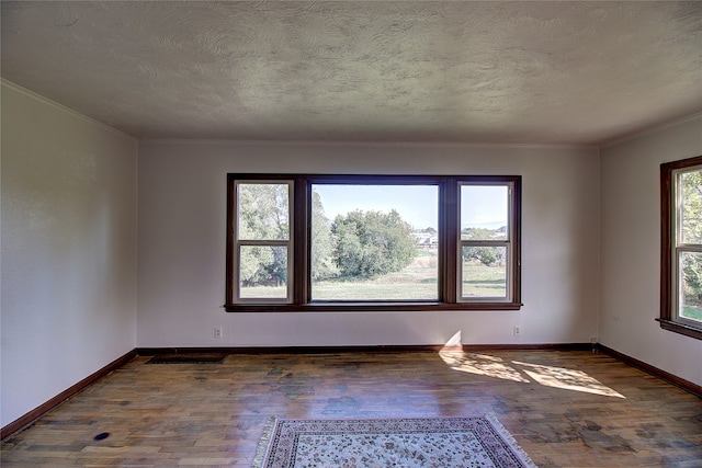 spare room featuring a textured ceiling, crown molding, and dark hardwood / wood-style flooring