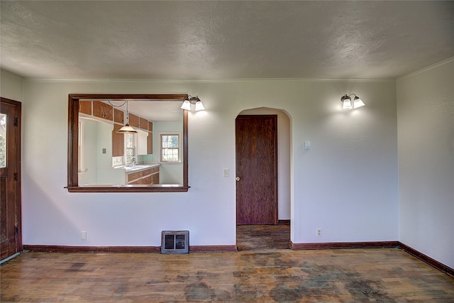 empty room featuring a textured ceiling, ornamental molding, sink, and wood-type flooring