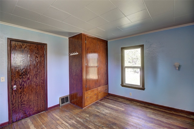 unfurnished bedroom with ornamental molding and dark hardwood / wood-style floors