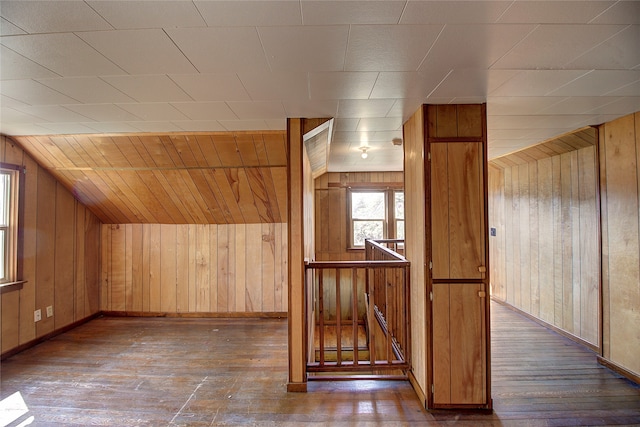 bonus room with dark wood-type flooring and wood walls