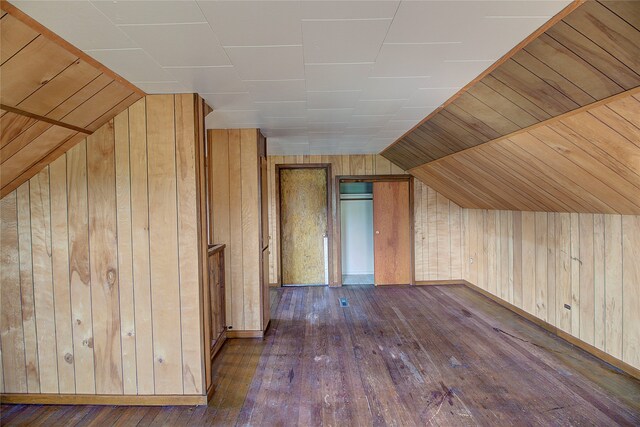 additional living space featuring vaulted ceiling, wooden walls, and dark hardwood / wood-style flooring