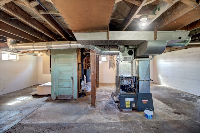 basement featuring a wealth of natural light, water heater, and heating unit