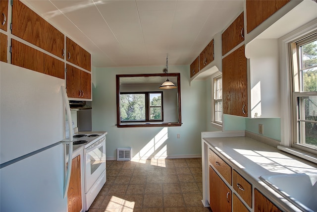 kitchen with white appliances, a wealth of natural light, and dark tile patterned floors