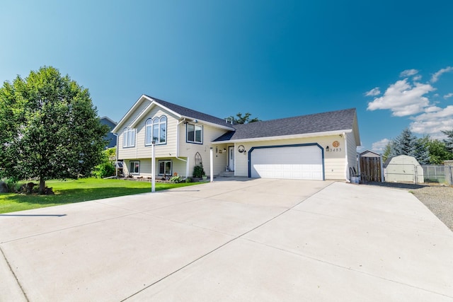 split level home featuring a garage, driveway, a front yard, and fence