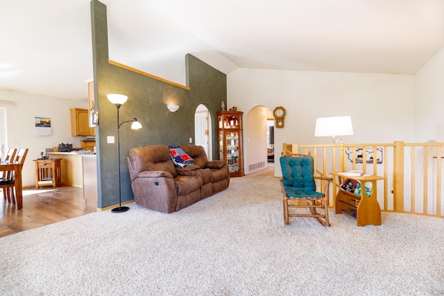 living room with visible vents, arched walkways, light colored carpet, and lofted ceiling