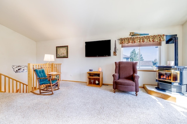 living area featuring baseboards, carpet floors, an upstairs landing, and a wood stove