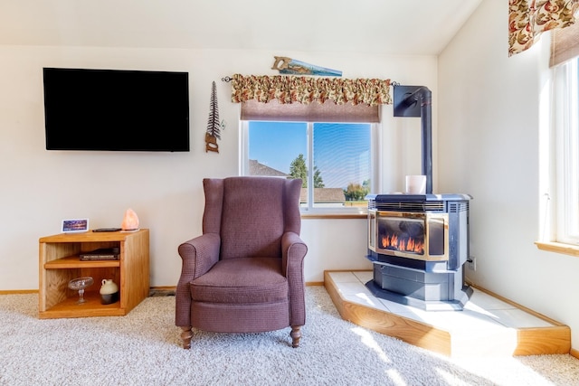 living area with plenty of natural light, a wood stove, carpet, and vaulted ceiling