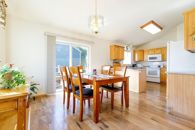 dining area featuring light wood-type flooring, a notable chandelier, and vaulted ceiling