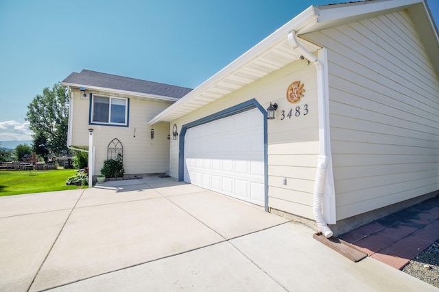 view of side of home featuring concrete driveway and an attached garage