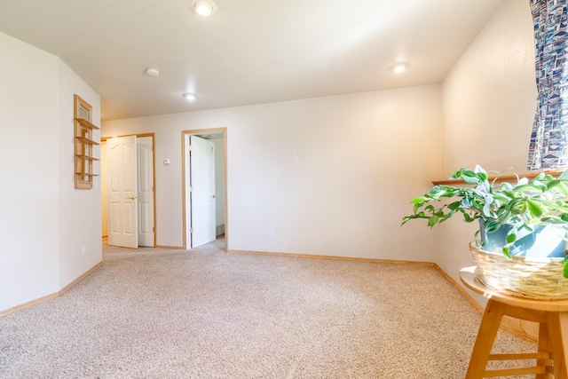 spare room featuring baseboards and light carpet