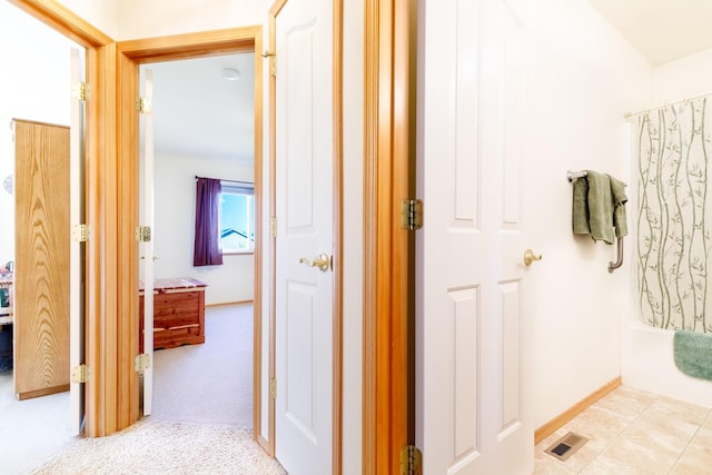 hall with visible vents, light carpet, and baseboards