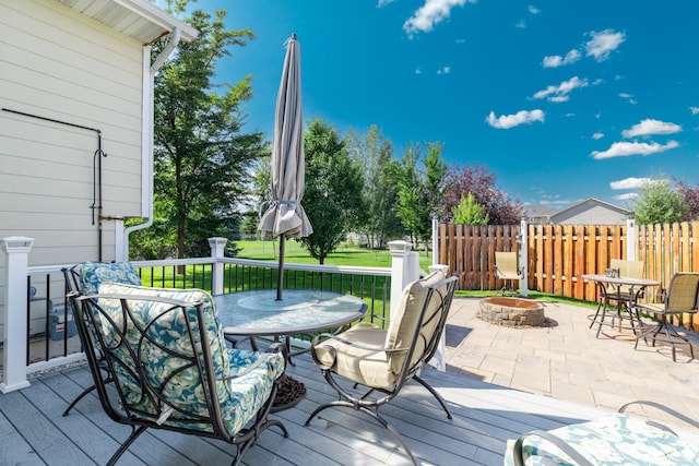 wooden terrace featuring a fire pit, fence, and a lawn