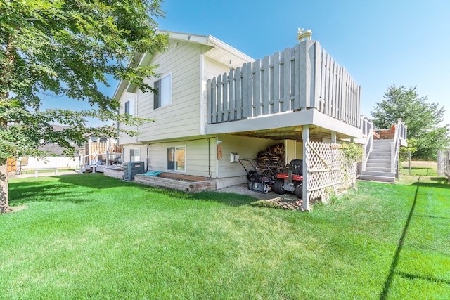 back of property featuring central air condition unit, stairway, a yard, and a wooden deck