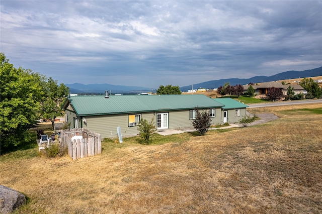 rear view of property with metal roof, a yard, and a mountain view