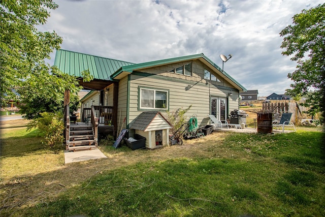 back of house with metal roof and a lawn