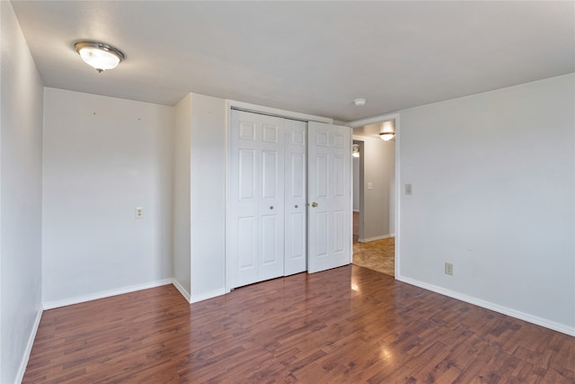 unfurnished bedroom with baseboards, dark wood finished floors, and a closet