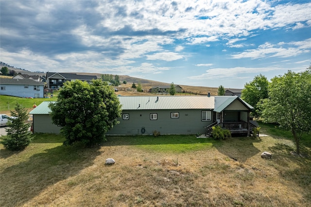 back of property featuring metal roof and a yard