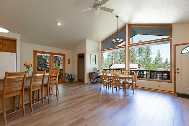 dining space featuring vaulted ceiling, ceiling fan with notable chandelier, and light wood-style floors