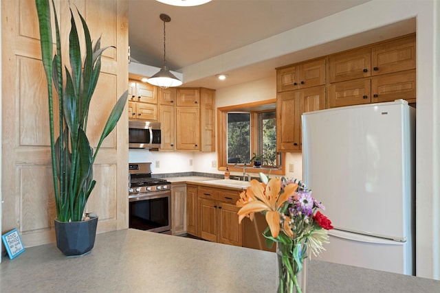 kitchen featuring light countertops, appliances with stainless steel finishes, a sink, and pendant lighting