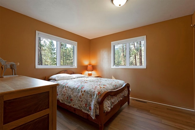 bedroom featuring visible vents, baseboards, and wood finished floors