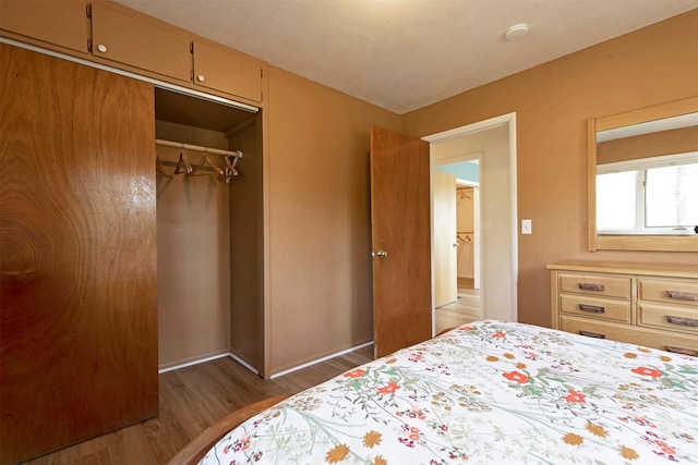 bedroom featuring a closet, baseboards, and wood finished floors