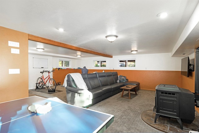 rec room with a wood stove, carpet, beam ceiling, and a healthy amount of sunlight