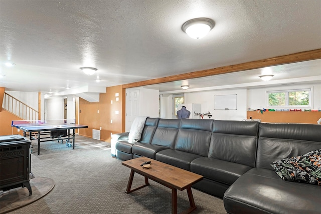 carpeted living room featuring beam ceiling, visible vents, a textured ceiling, and stairs