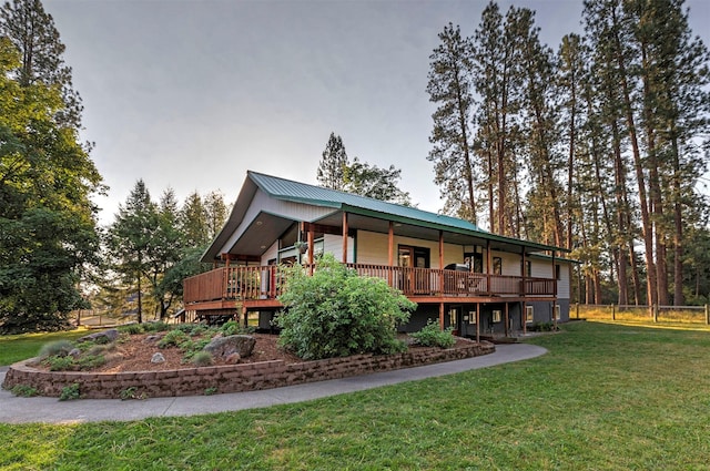 rear view of house featuring metal roof, a yard, a deck, and fence