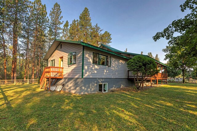 view of property exterior with stairway, a lawn, fence, and a wooden deck