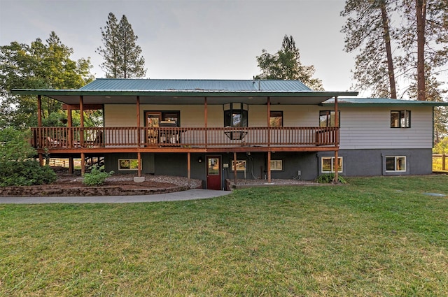 rear view of property featuring metal roof, a lawn, and a deck