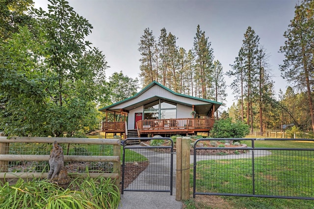 view of front of house featuring a front lawn, a fenced front yard, a wooden deck, and a gate