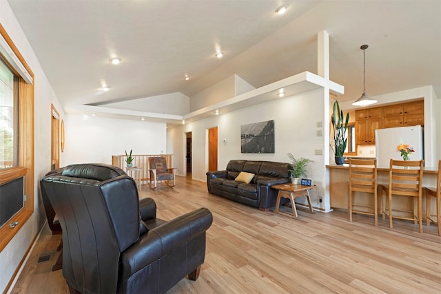 living area with high vaulted ceiling, light wood-style flooring, and visible vents