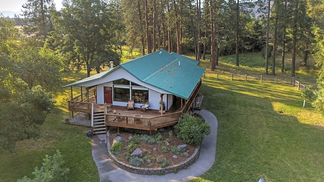 view of front of home with a wooden deck, fence, metal roof, and a front yard