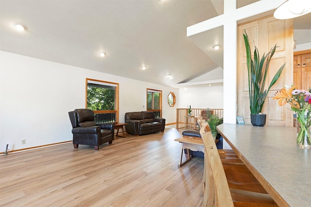 living room featuring high vaulted ceiling, light wood finished floors, and baseboards