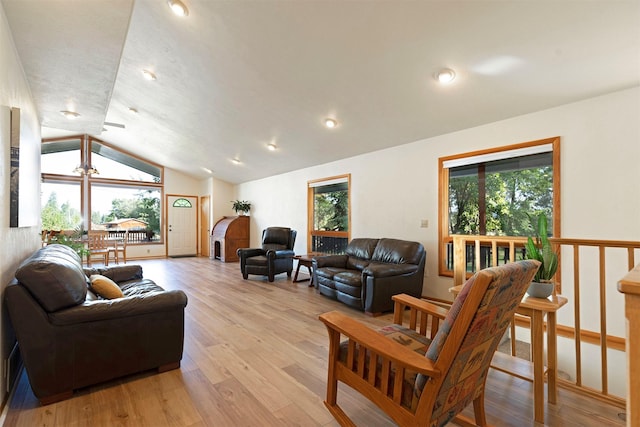 living area with light wood-type flooring, plenty of natural light, and lofted ceiling