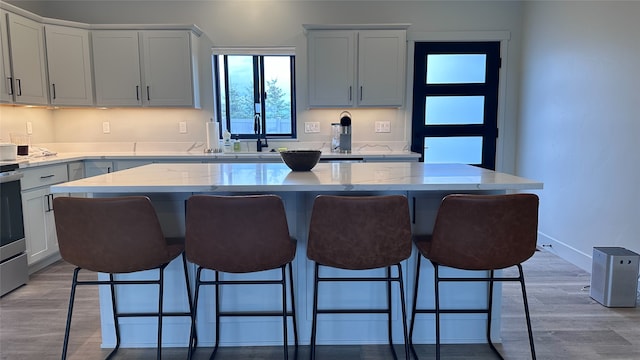 kitchen featuring light stone counters, range, light wood-type flooring, a kitchen breakfast bar, and a center island