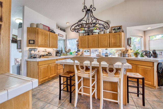 kitchen with a breakfast bar, lofted ceiling, and tile counters