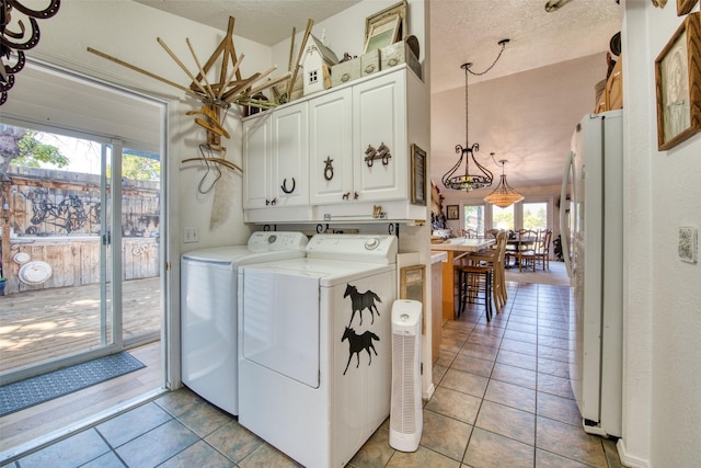 clothes washing area with washer and dryer, light tile patterned floors, cabinet space, and a textured ceiling