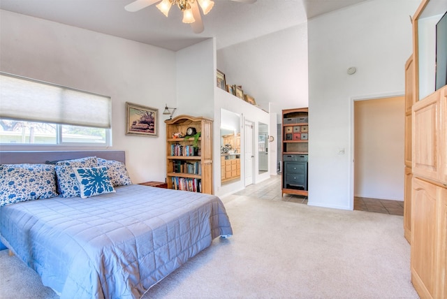 bedroom featuring a ceiling fan, high vaulted ceiling, light tile patterned flooring, ensuite bathroom, and light carpet