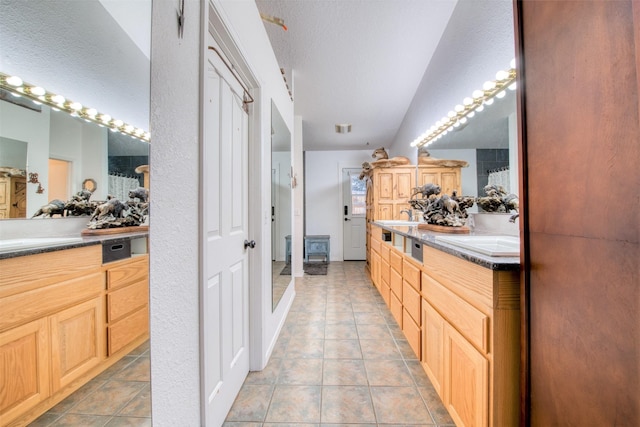 bathroom featuring a sink, vaulted ceiling, double vanity, and tile patterned flooring