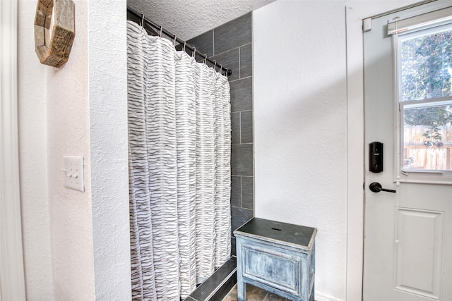 full bathroom with a shower with shower curtain, a textured wall, and a textured ceiling