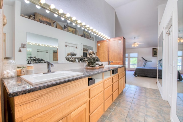 ensuite bathroom featuring tile patterned floors, ensuite bath, a towering ceiling, and a sink