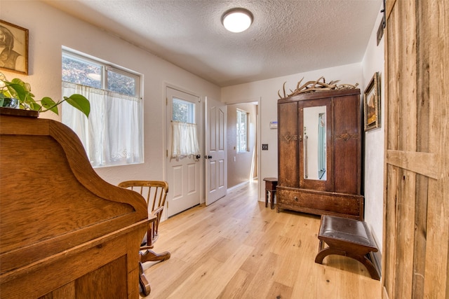 foyer entrance with light wood-style flooring and a textured ceiling