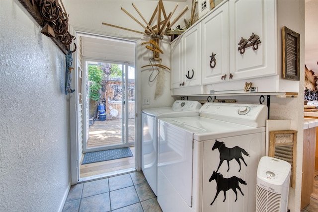 laundry room with washing machine and dryer, light tile patterned floors, cabinet space, and a textured wall