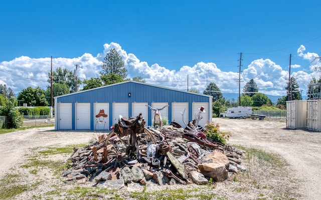 detached garage featuring fence and dirt driveway