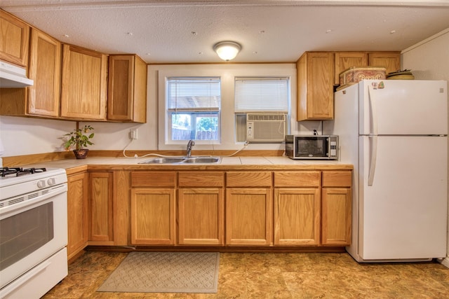 kitchen with tile counters, under cabinet range hood, cooling unit, white appliances, and a sink